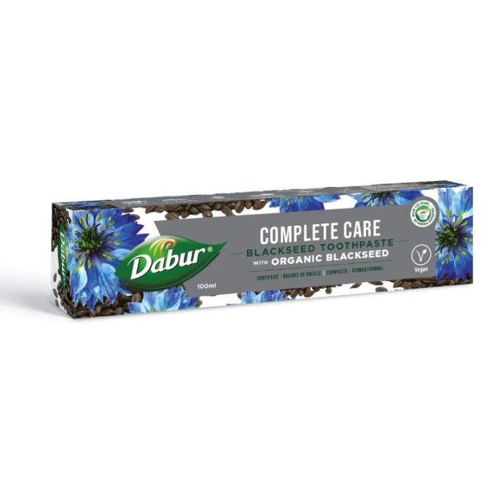 Dabur Complete Care Schwarzkümmel Zahnpasta Faltschachtel mit Blaue-Kornblumen-Motiv und Samen.