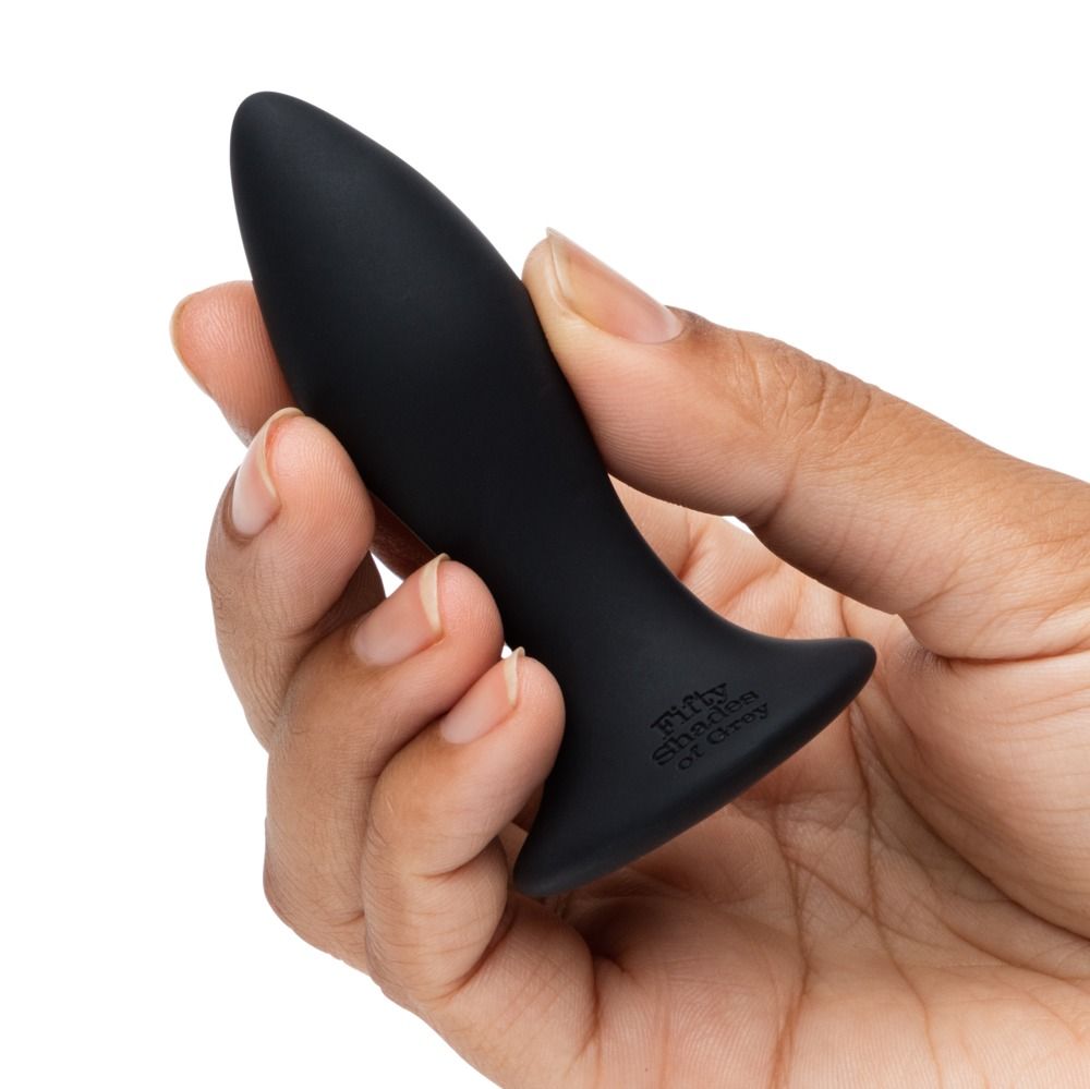 Schwarzer Analplug in einer Hand gehalten. Basis mit Schriftzug 'Fifty Shades of Grey'.