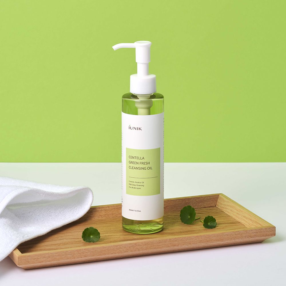 iUNIK Centella Green Fresh Cleansing Oil auf einem Holztablett mit Handtuch.