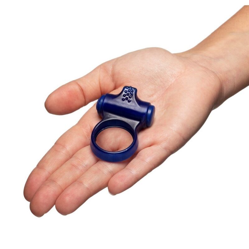 Blauer Vibrationsring in einer Hand. Ringförmiger Teil und erhabener Aufsatz mit Noppen. Produkt liegt auf offener Handfläche.