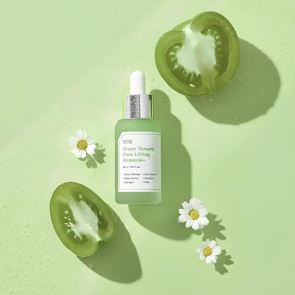 Grünes Serumfläschchen, grüne Tomatenhälften und Gänseblümchen auf grünem Hintergrund.