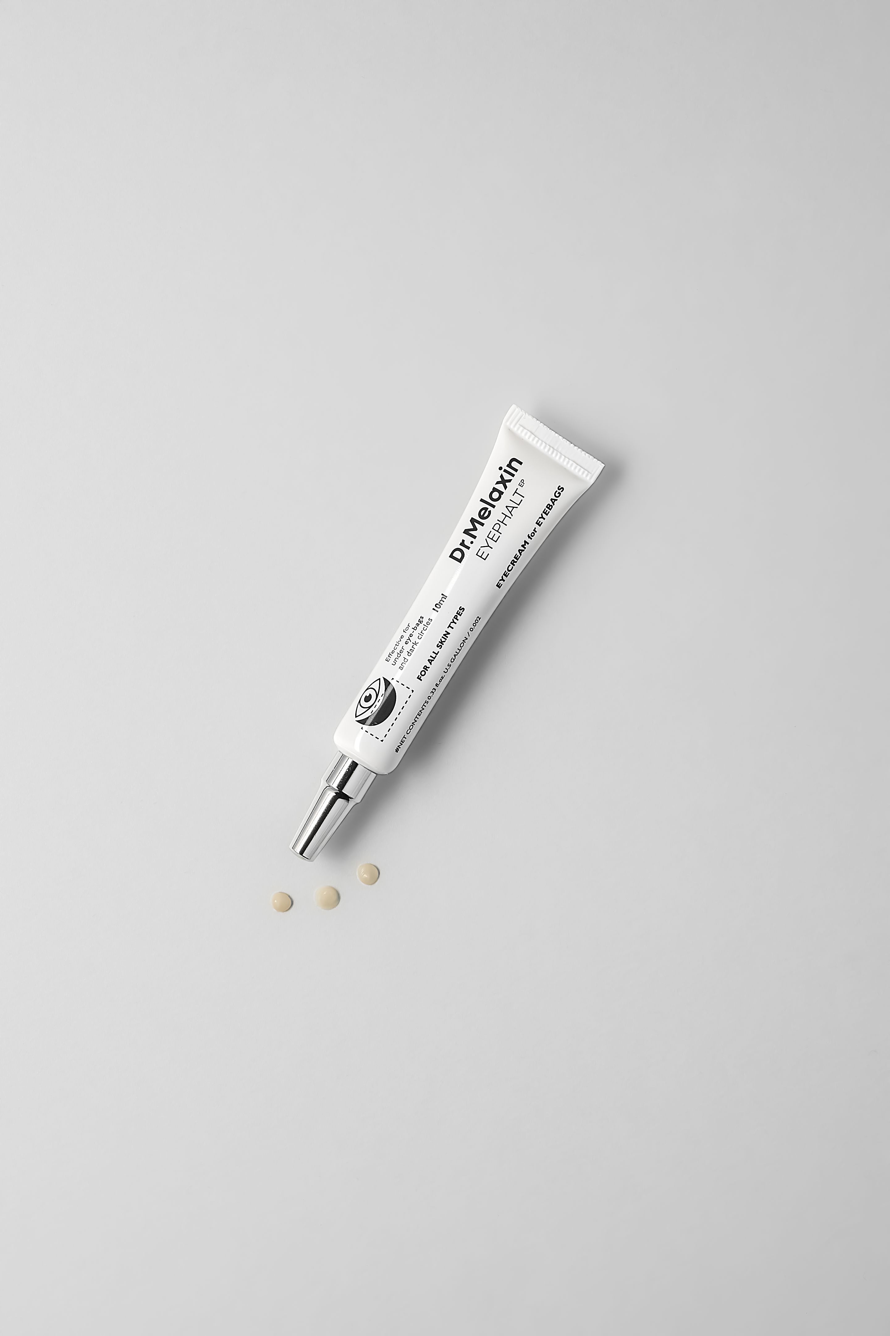 Weiße Tube mit Creme und Tropfen. Text: Dr.Melaxin EYEPHALT. Creme und Tropfen auf weißem Hintergrund.