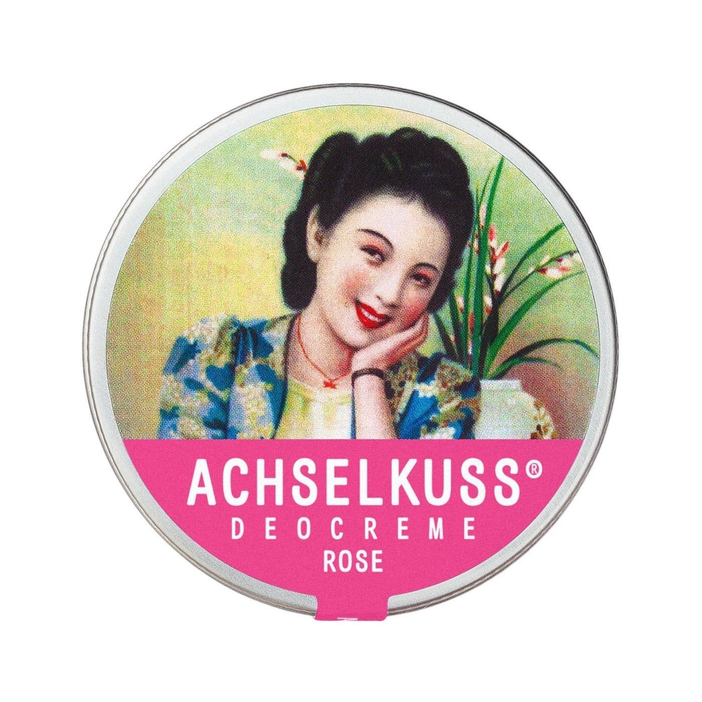 Runde Dose mit Deckel. Auf dem Deckel ist eine Frau abgebildet. Darunter steht in Rosa: ACHSELKUSS DEOCREME ROSE.