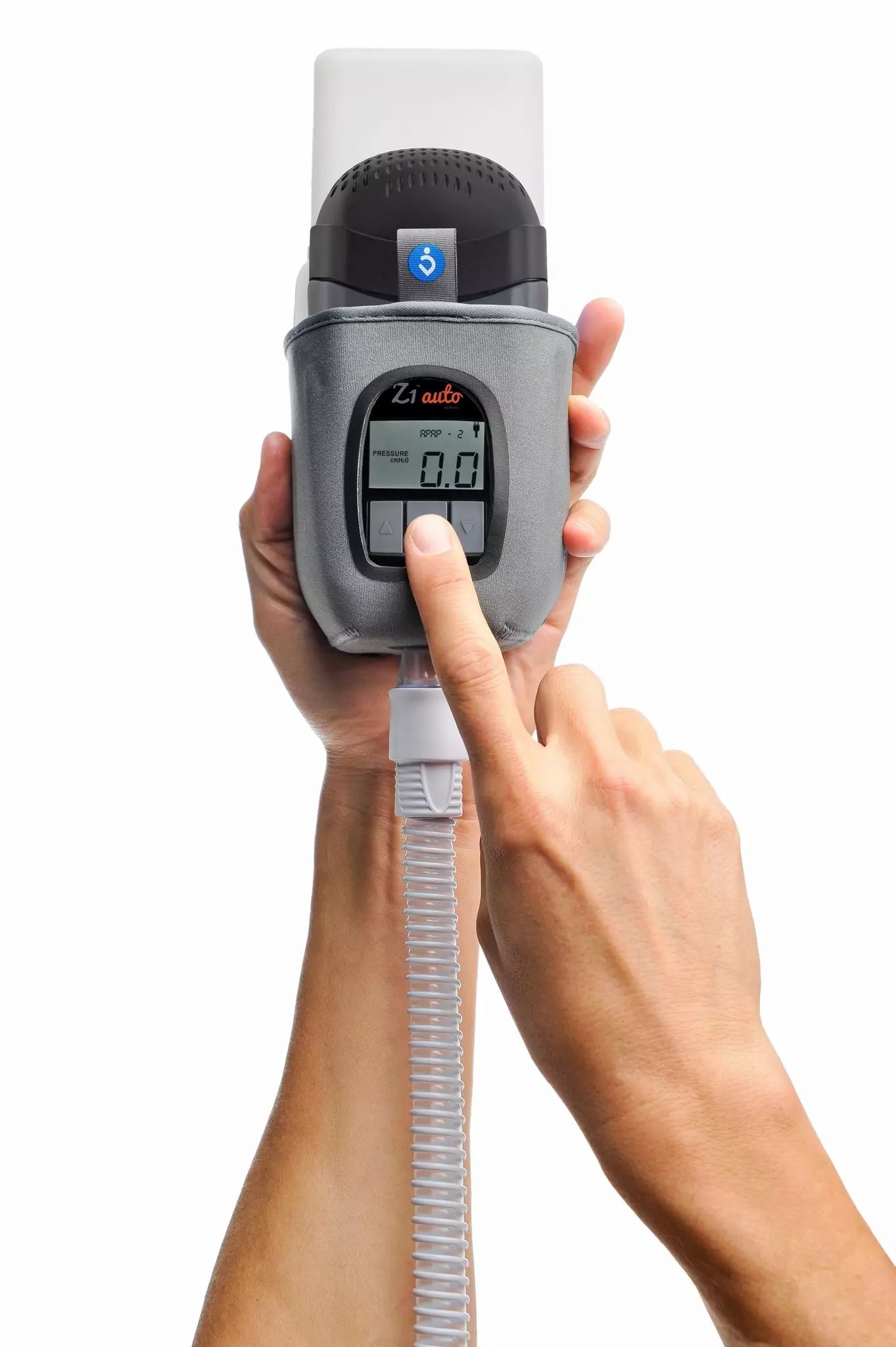Graues Reise-CPAP-Gerät mit Display und Schläuchen, von Händen gehalten.
