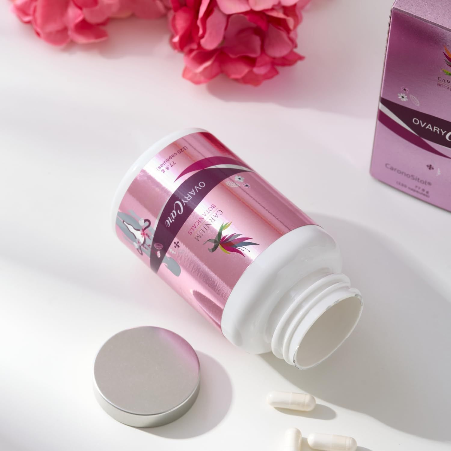 Pillenbehälter mit rosa Etikett, geöffnet, daneben Kapseln. Aufschrift: CARNIUM BOTANICALS, OVARY Care.