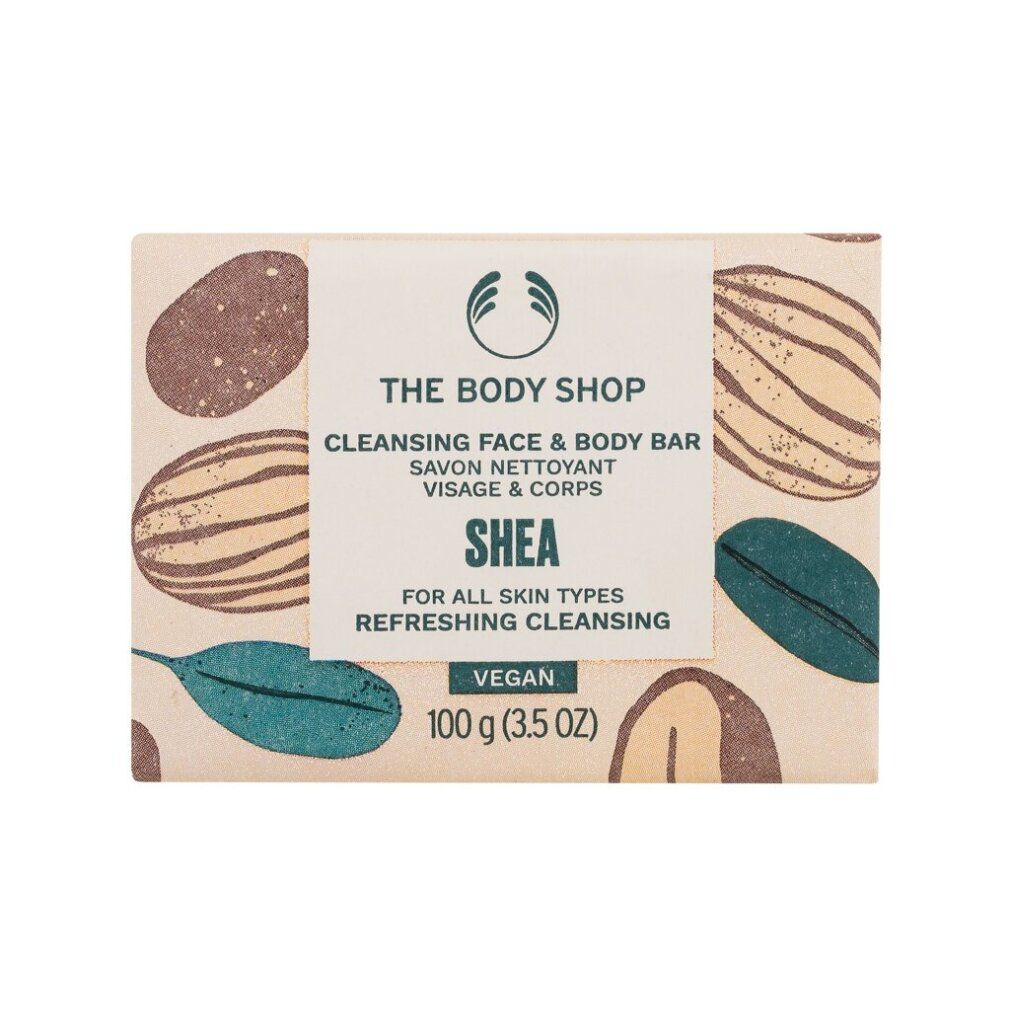 Seife mit Verpackung. Aufschrift: The Body Shop, Cleansing Face & Body Bar, Shea, Vegan. 100 g. Mit braunen und grünen Mustern.