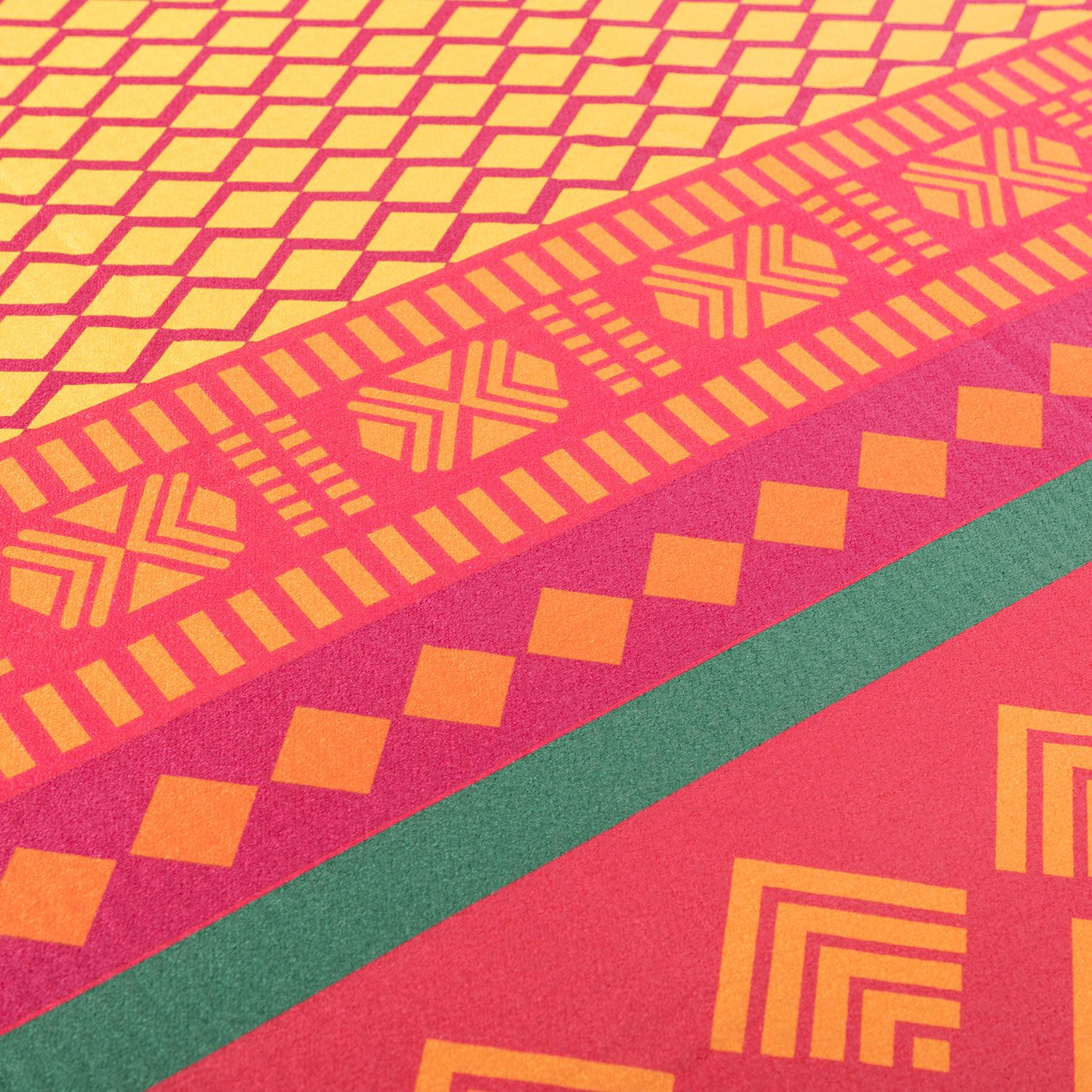 Nahaufnahme eines Yoga-Handtuchs. Rot, gelb und grün mit geometrischen Mustern und grünen Akzenten.