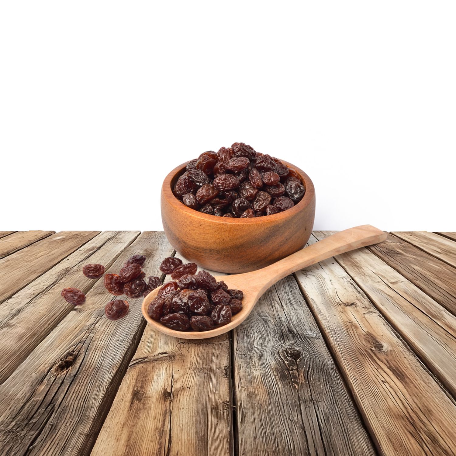 Schwarze Rosinen in einer Holzschale und einem Holzlöffel.