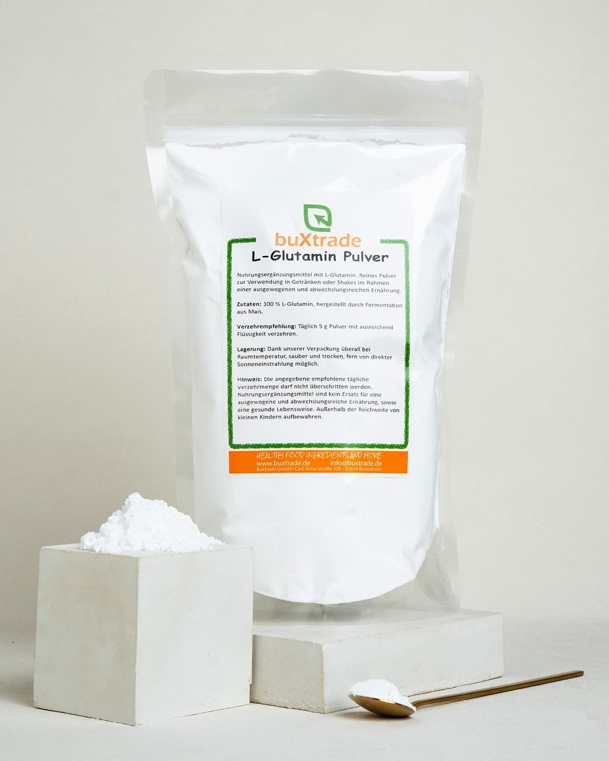 Buxtrade L-Glutamin Pulver in weißer Verpackung, daneben ein Würfel mit Pulver und ein Löffel.