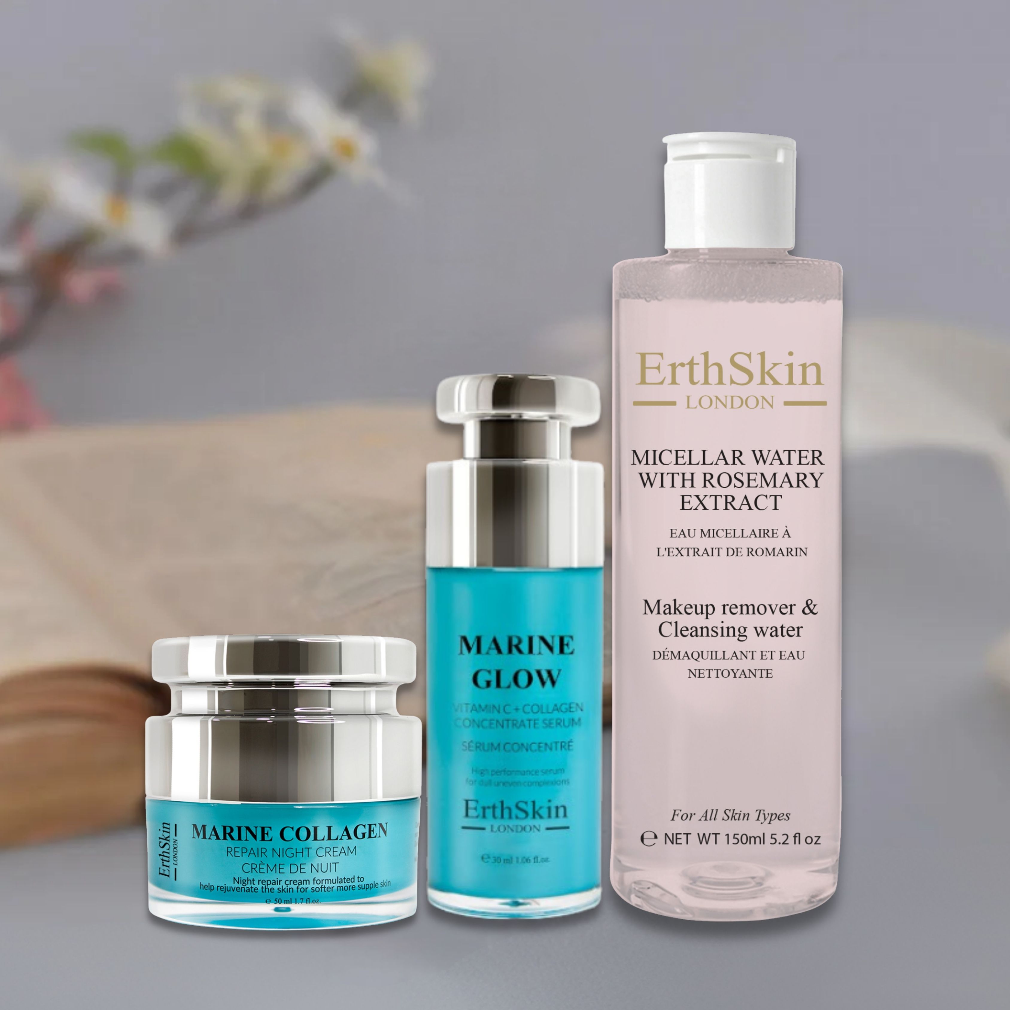 Drei Hautpflegeprodukte: Nachtcreme, Serum und Mizellenwasser. Blaue und silberne Behälter mit Produktnamen und Markennamen. Buch im Hintergrund.