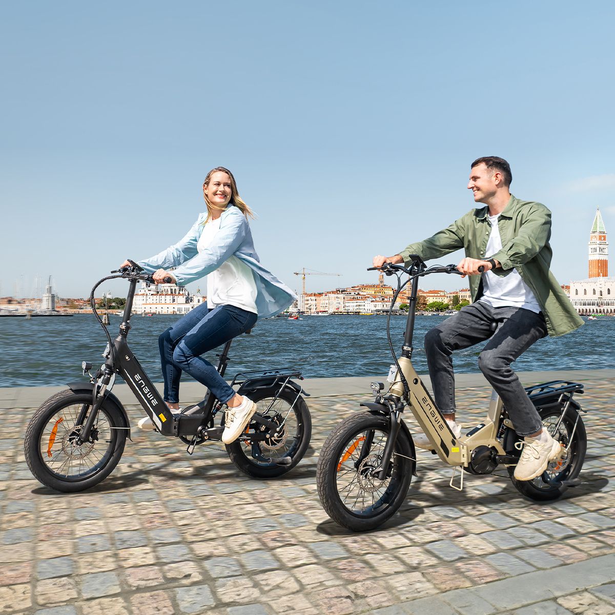 Zwei Personen fahren auf E-Bikes. Eine Person auf einem schwarzen, die andere auf einem beigen ENGWE L20 3.0 Pro.