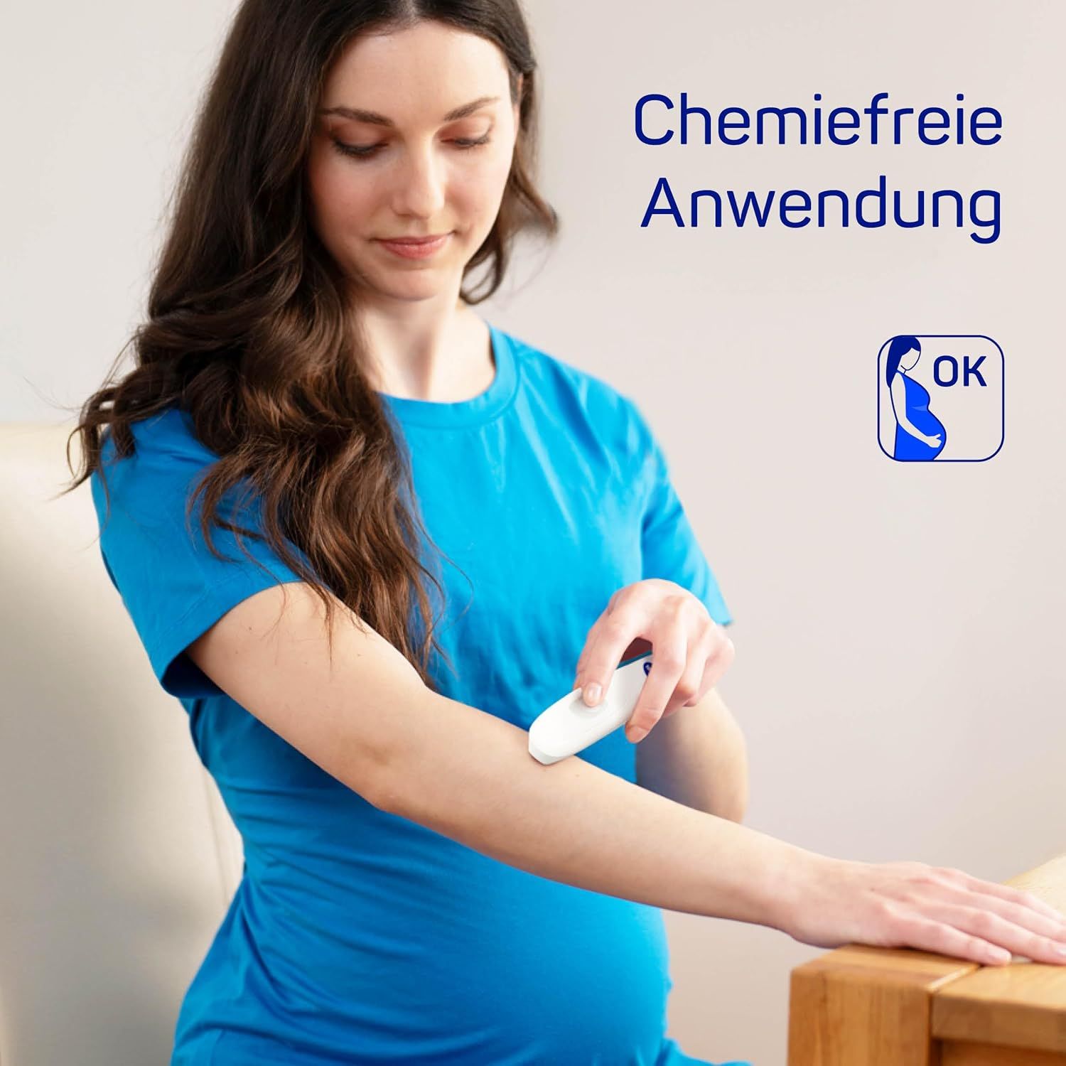 Schwangere Frau benutzt ein weißes, stiftförmiges Gerät am Arm. OK-Symbol.