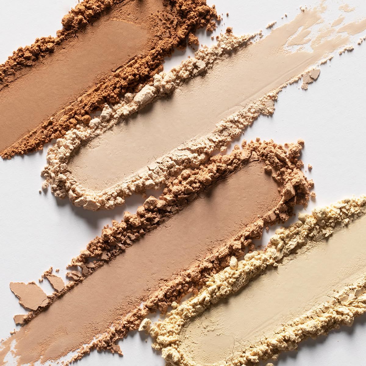 Mehrere Puderstreifen in verschiedenen Farbtönen. Von hell bis dunkelbraun. Auf weißem Hintergrund.