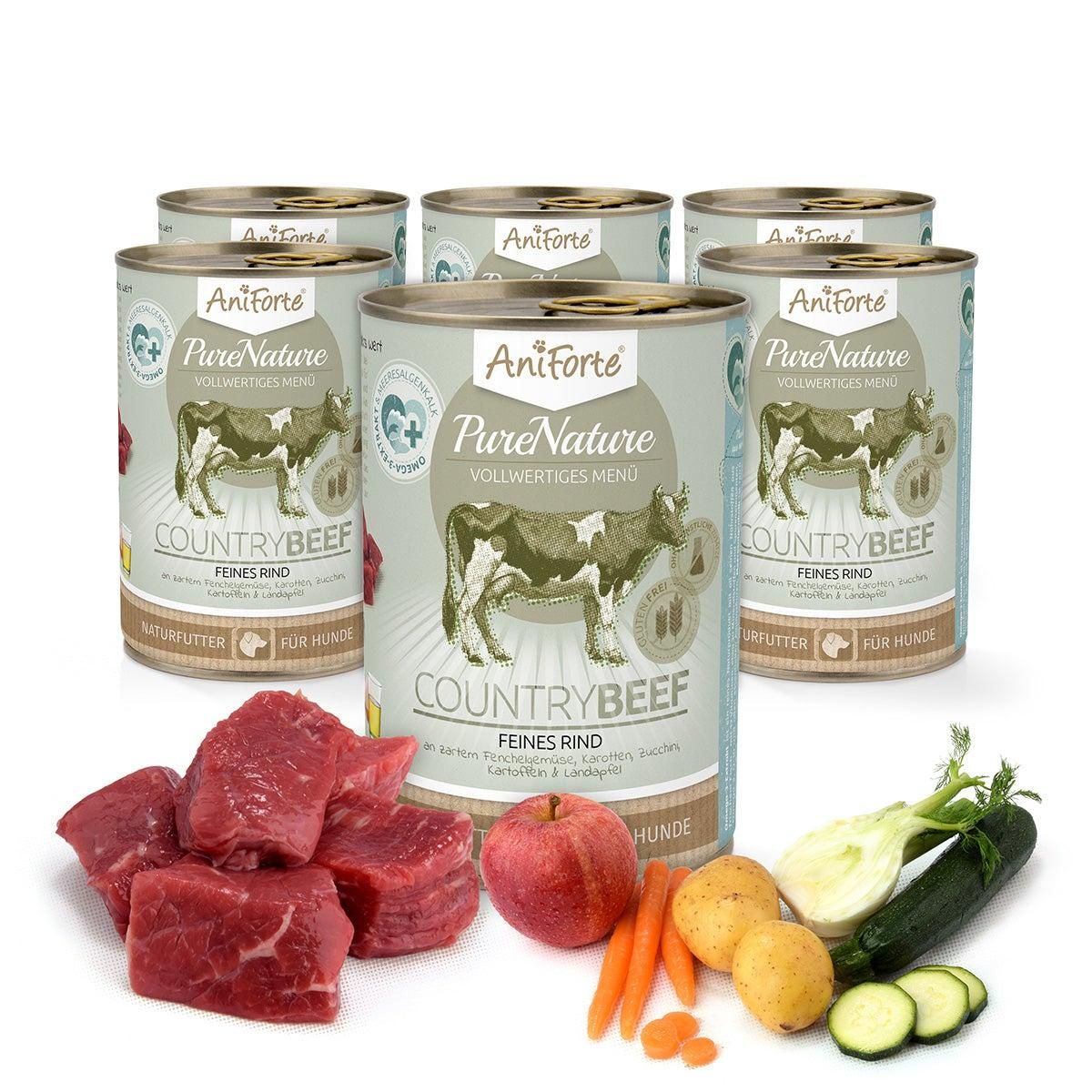 Sechs Dosen Aniforte CountryBeef Nassfutter. Rindfleisch, Gemüse und Obst daneben. Auf hellem Untergrund.