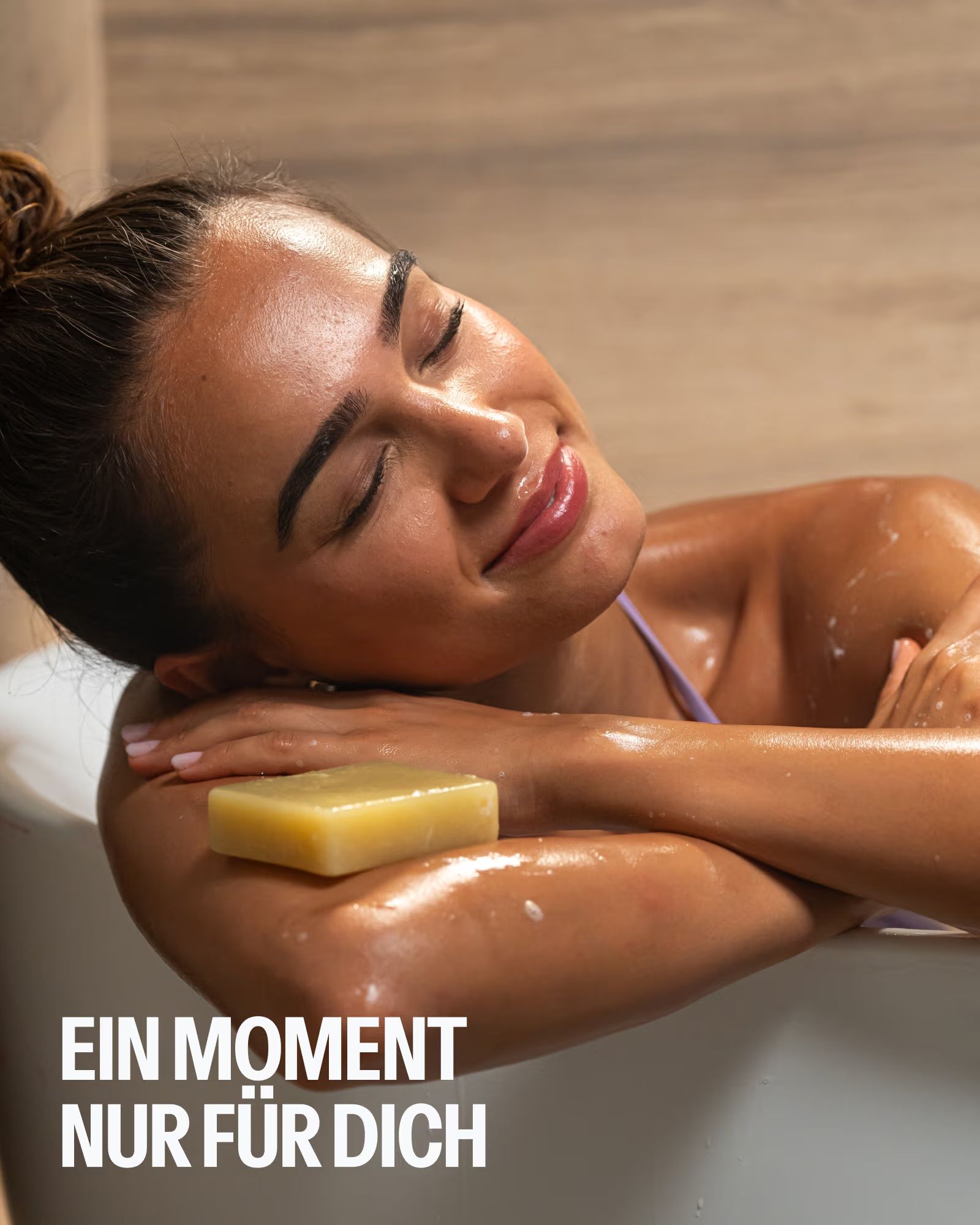 Frau entspannt in der Badewanne mit SOURCE LAB Pflegeseife auf dem Arm.