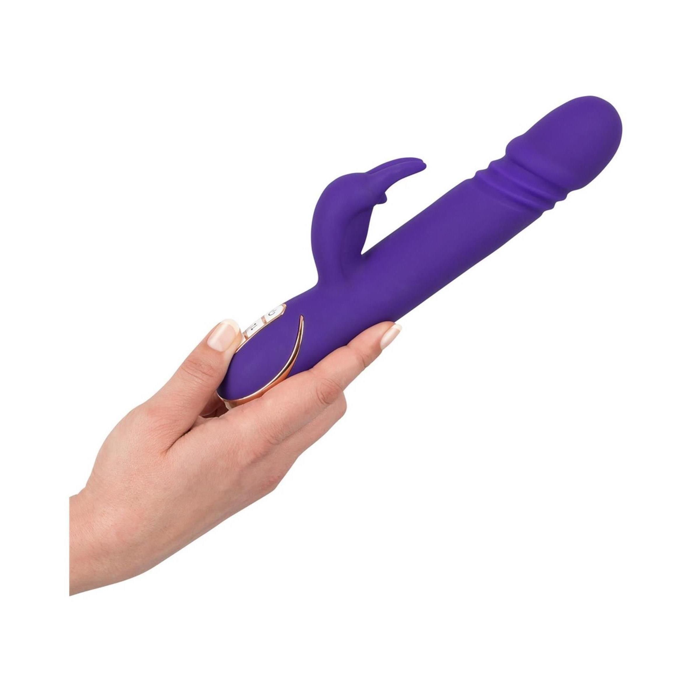 Hand hält lila Vibrator mit Hasenohren-Design. Goldfarbene Akzente.
