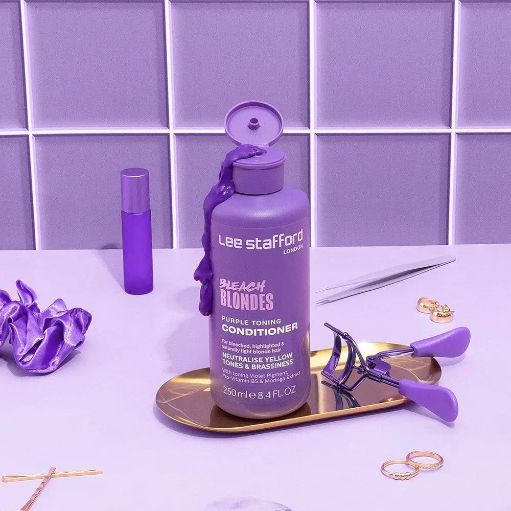 Lila Tönungsbalsam in einer Flasche mit aufgesetztem Deckel, daneben Haarschmuck und Make-up-Werkzeuge.