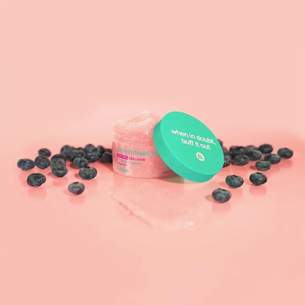 Offenes Peeling-Glas mit blauem Deckel und Heidelbeeren. Deckel mit Text: When in doubt, buff it out. Rosa Peeling-Inhalt sichtbar.