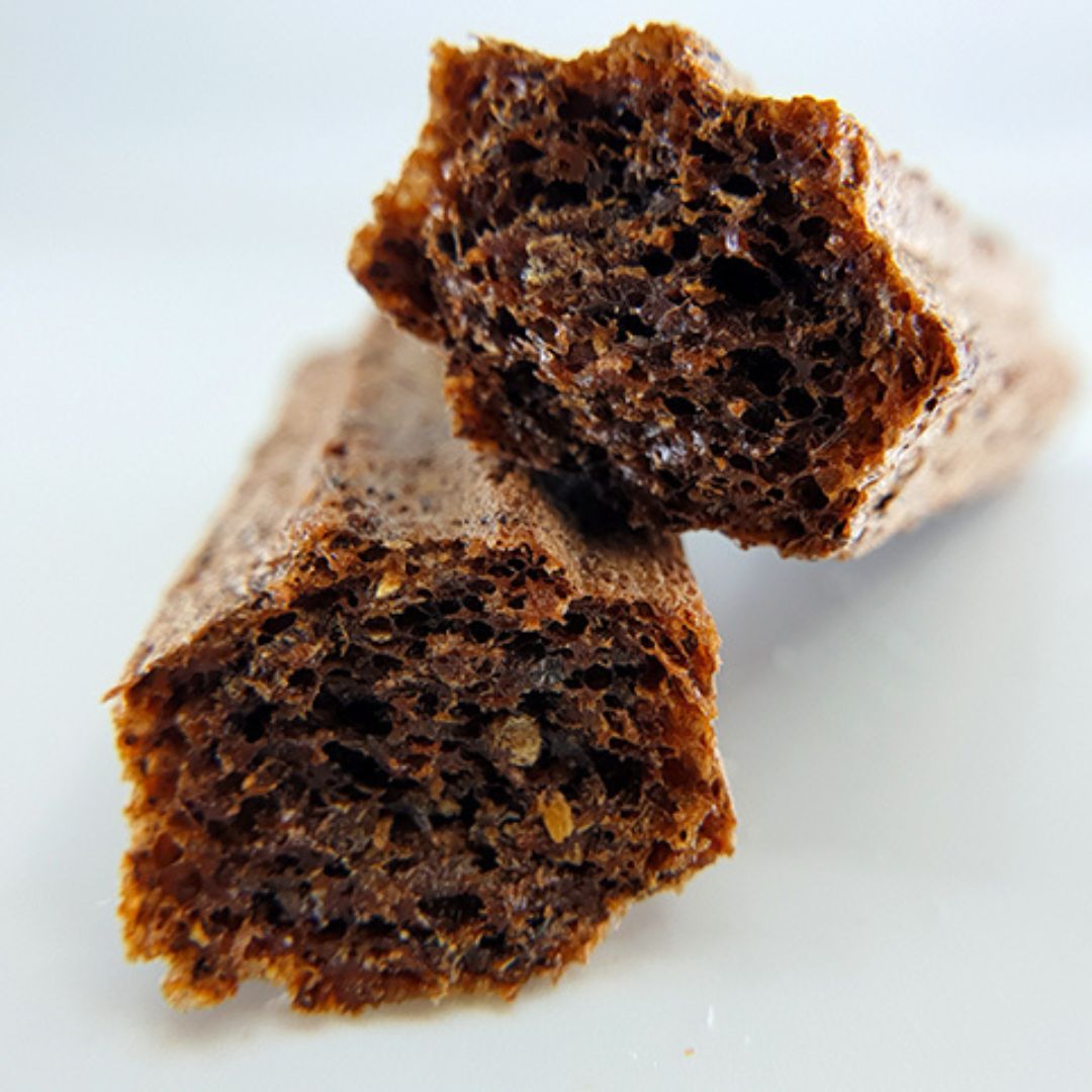 Nahaufnahme von zwei Puffed Crackern. Die Oberfläche ist uneben und weist eine dunkle, braune Farbe auf.