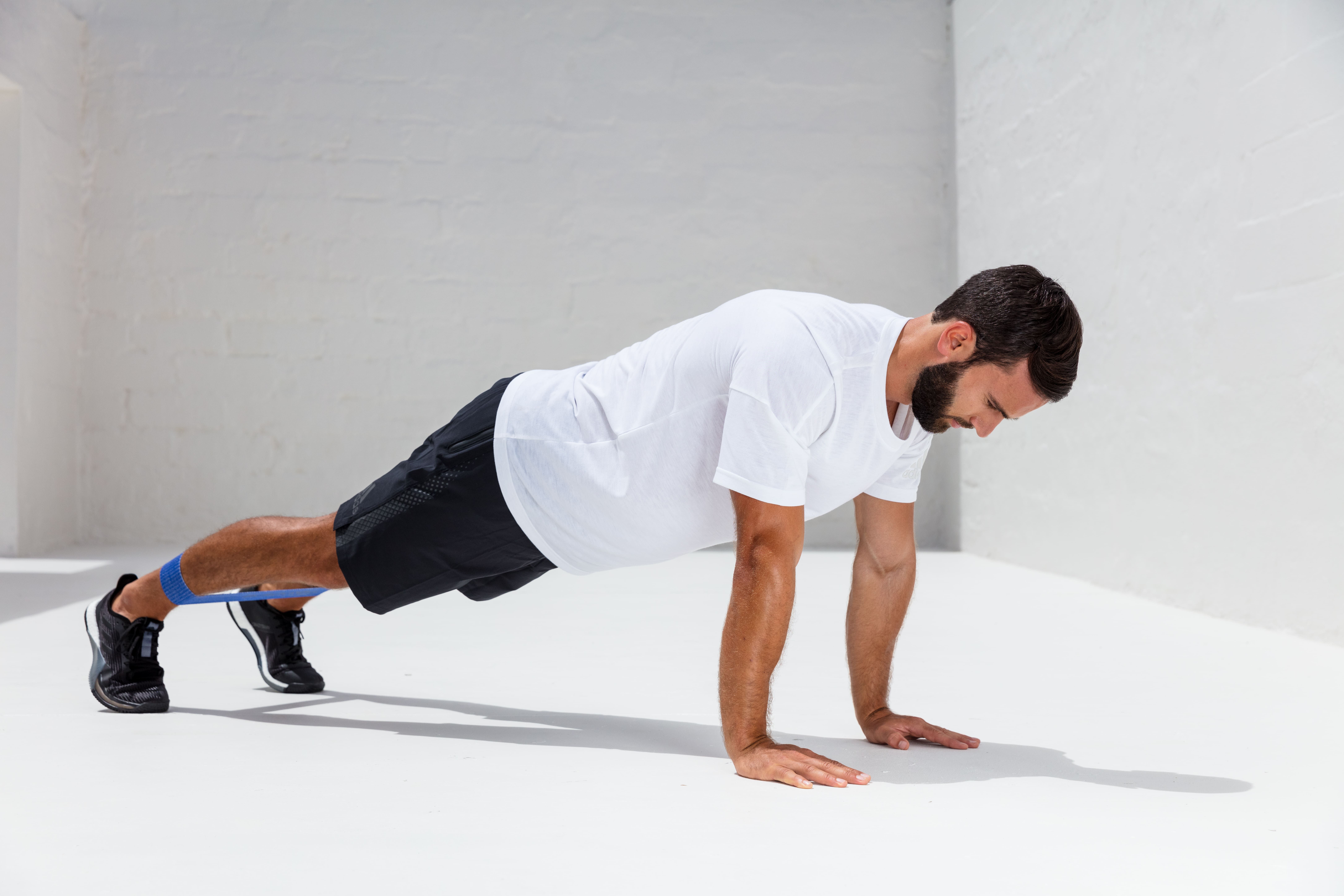 Mann trainiert mit blauer BLACKROLL Loop Band. Er macht Liegestütze.
