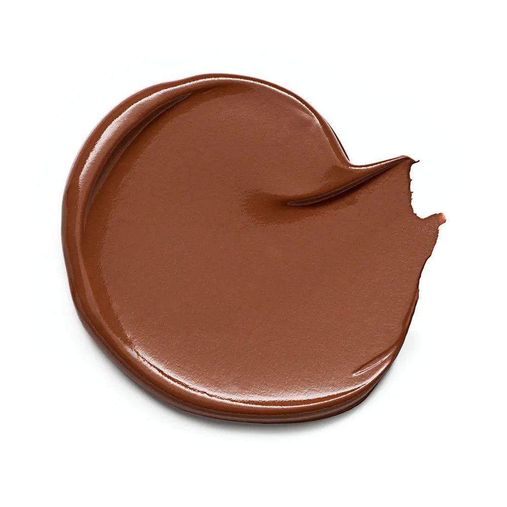 Ausgestrichene, braune Concealer-Probe auf weißem Hintergrund. Glänzende Textur.