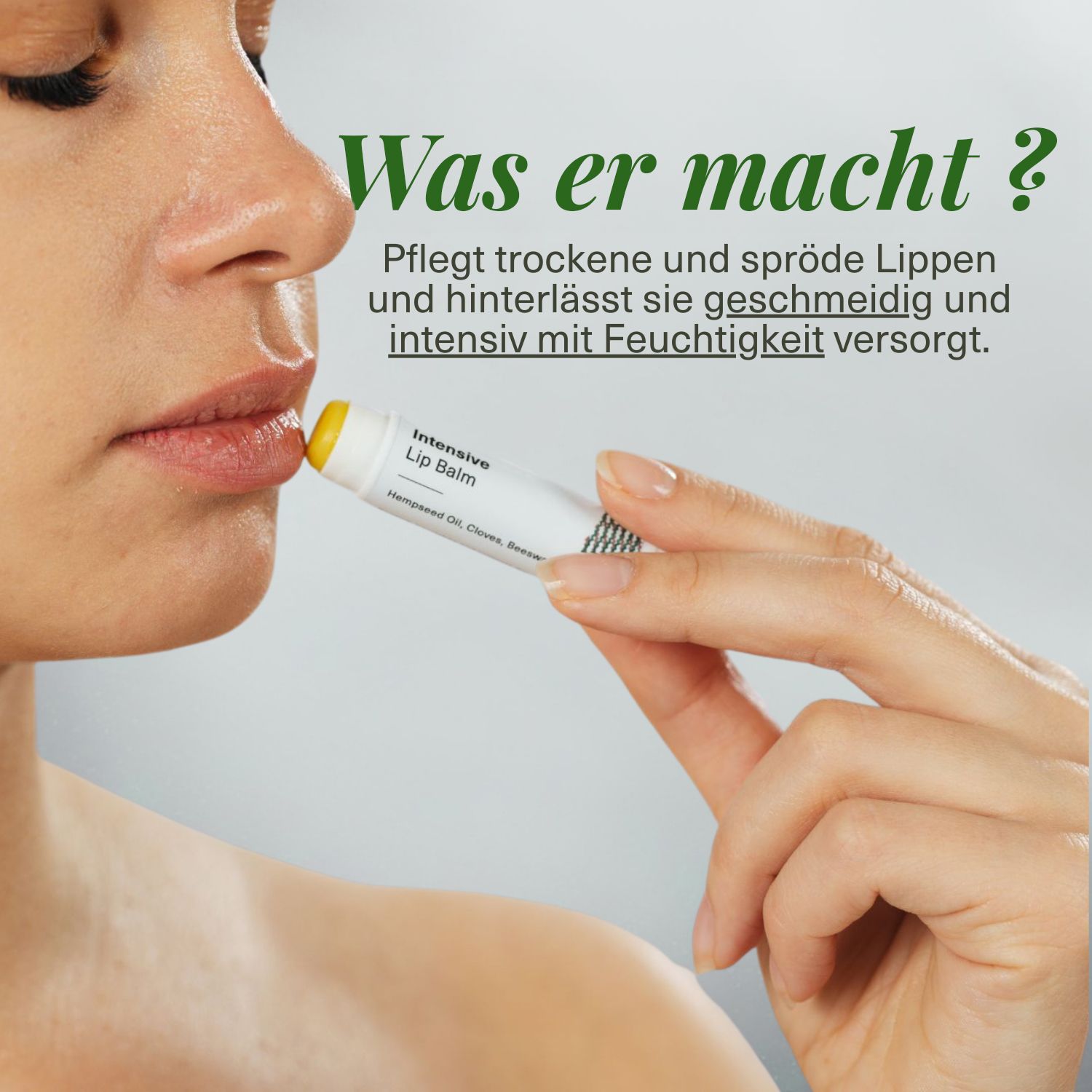 Eine Hand trägt einen Lippenbalsam-Stift auf die Lippen einer Person auf. Der Stift ist weiß mit schwarzer Schrift und gelbem Inhalt.