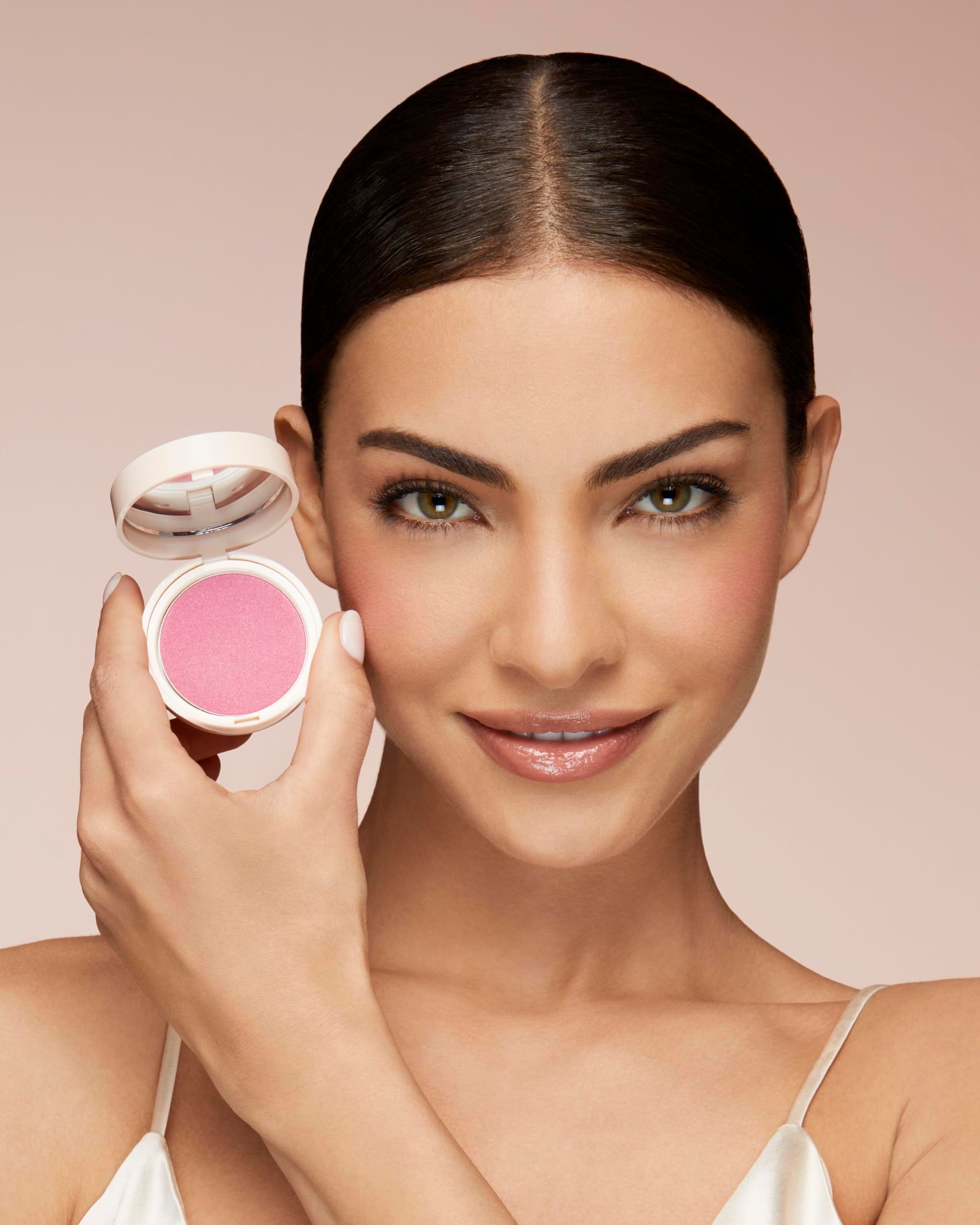 Frau hält Blush-Behälter. Rosa Blush auf den Wangen. Weißes Top.