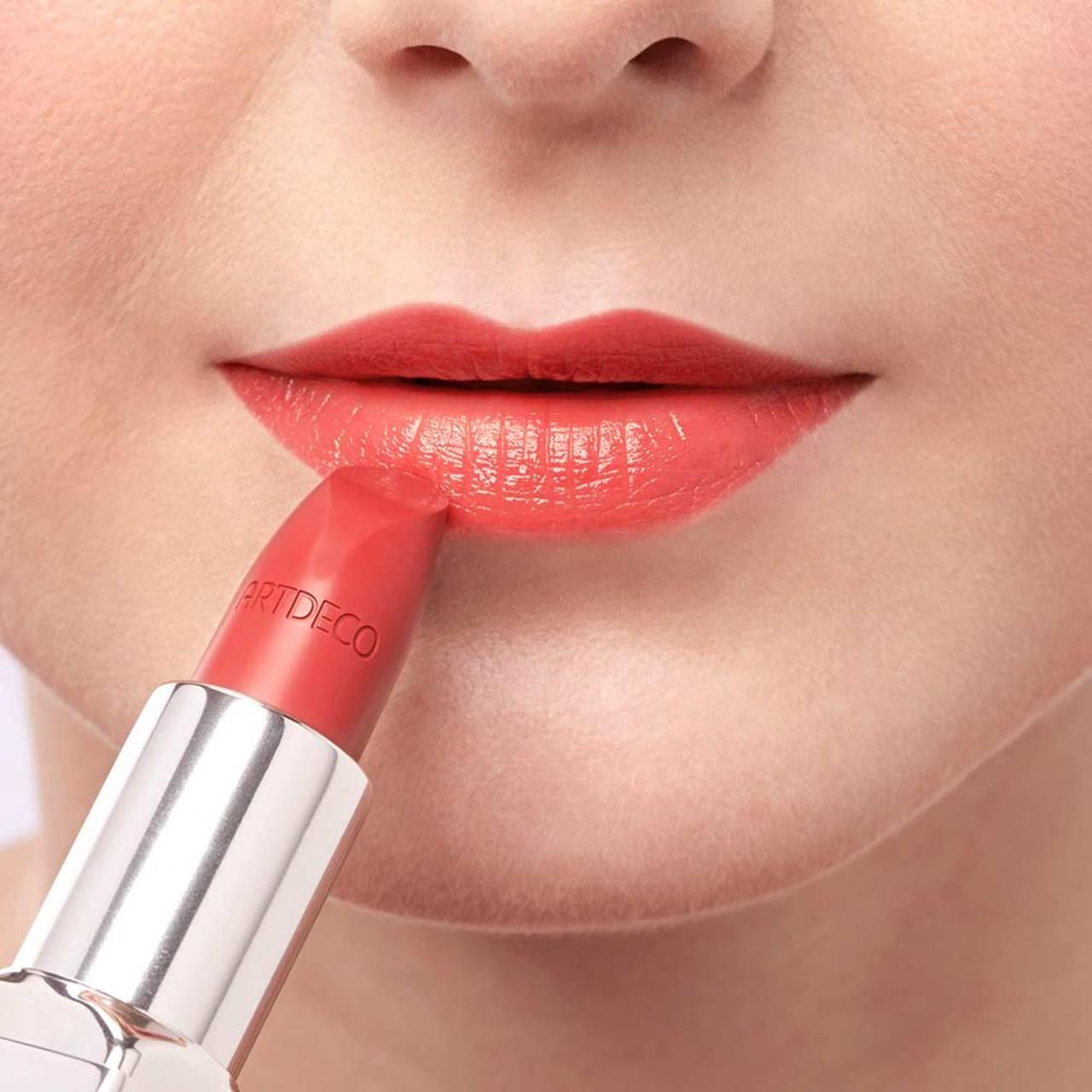 Person trägt rosafarbenen Lippenstift auf den Lippen auf. ARTDECO-Schriftzug auf dem Lippenstift.