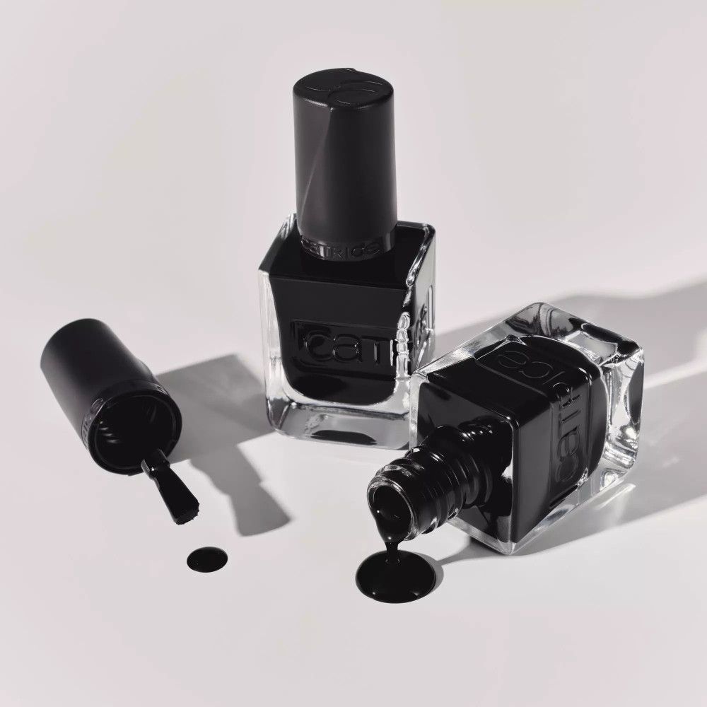 Drei Flaschen schwarzen Nagellacks. Eine mit Deckel, eine mit Pinsel, eine umgekippt mit Lack. Der Markenname CATRICE ist sichtbar.