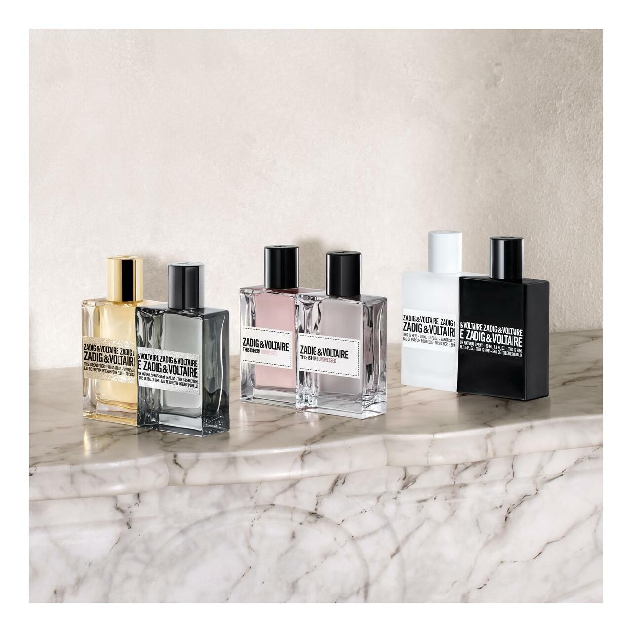 Sechs Parfümflakons in verschiedenen Farben. Aufschrift mit Markennamen und Produktbezeichnung. Auf Marmoroberfläche.