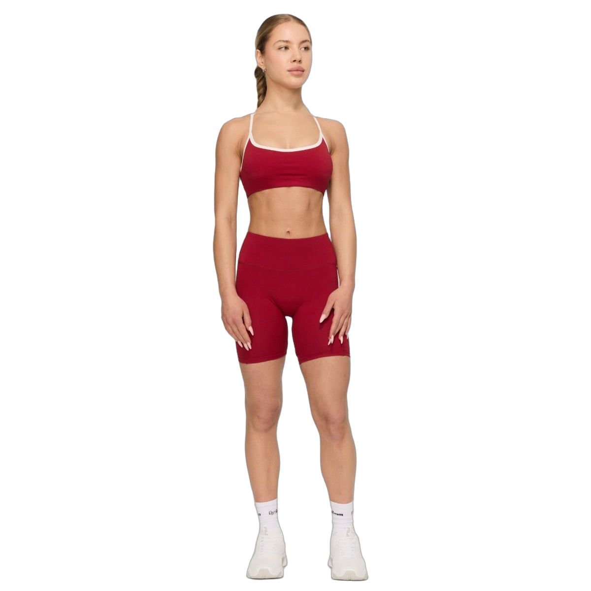 Frau in roten Sport-Shorts und passendem Sport-BH, weiße Socken und Schuhe.