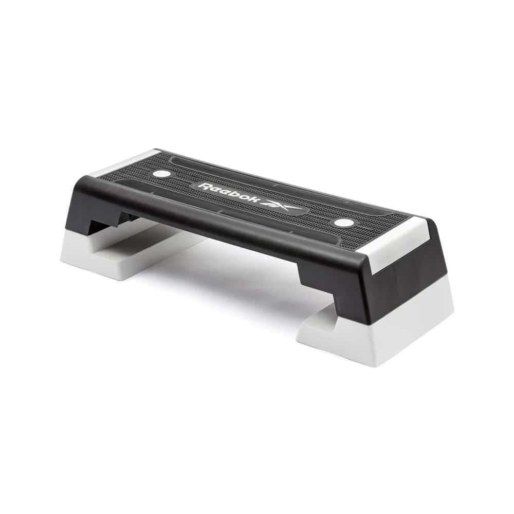 Reebok Step. Schwarze Trittfläche mit weißem Logo, weiße Füße. Rechteckige Form. Für Fitness-Übungen.