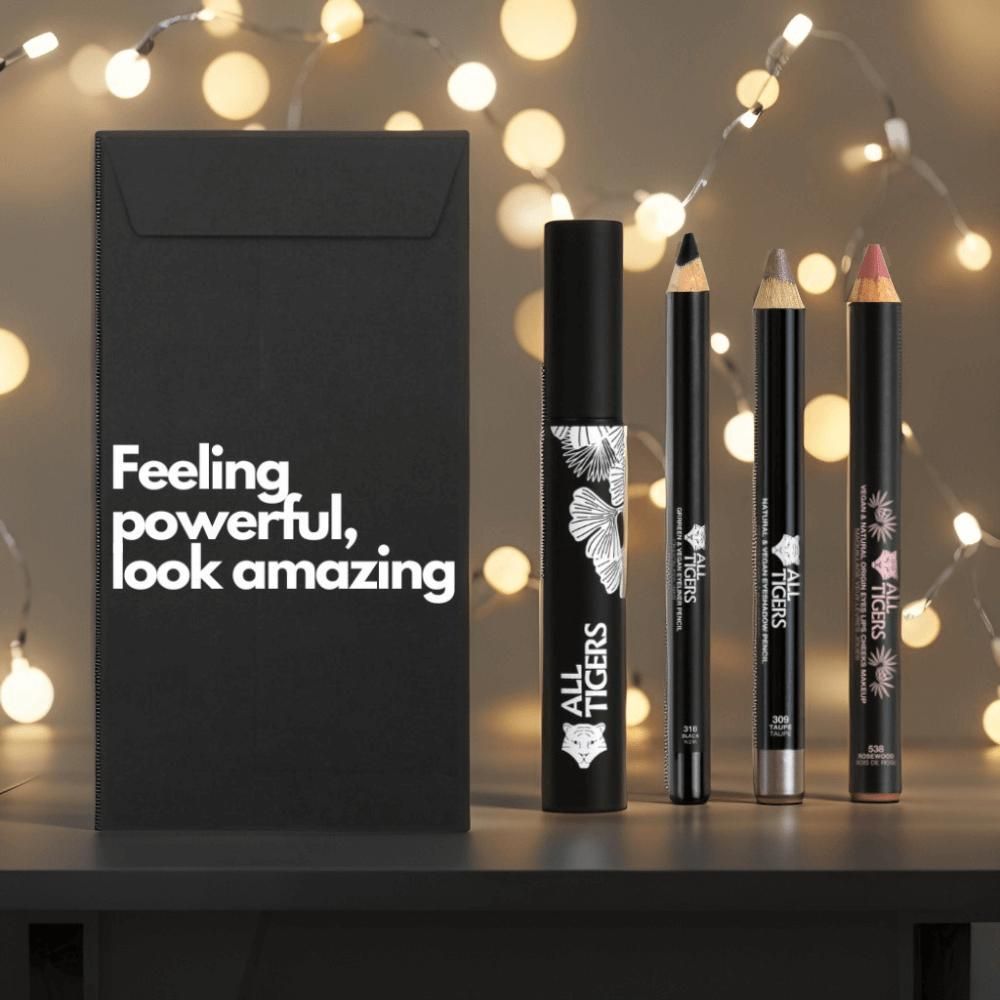 Schwarze Geschenkbox mit Text. Daneben Mascara, zwei Stifte und ein Lippenstift. Alle Produkte tragen das Logo.