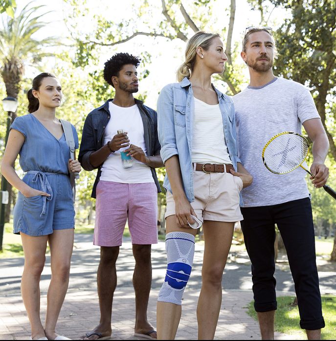 Gruppe von Menschen im Park. Eine Person trägt eine Kniebandage. Die Bandage ist blau und grau.