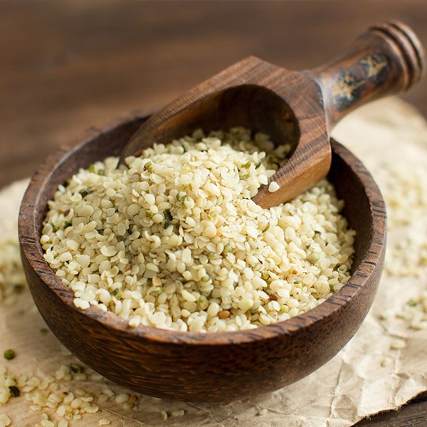 Hanfsamen in einer Holzschale mit Holzschaufel. Auf braunem Papier, Hintergrund Holz.