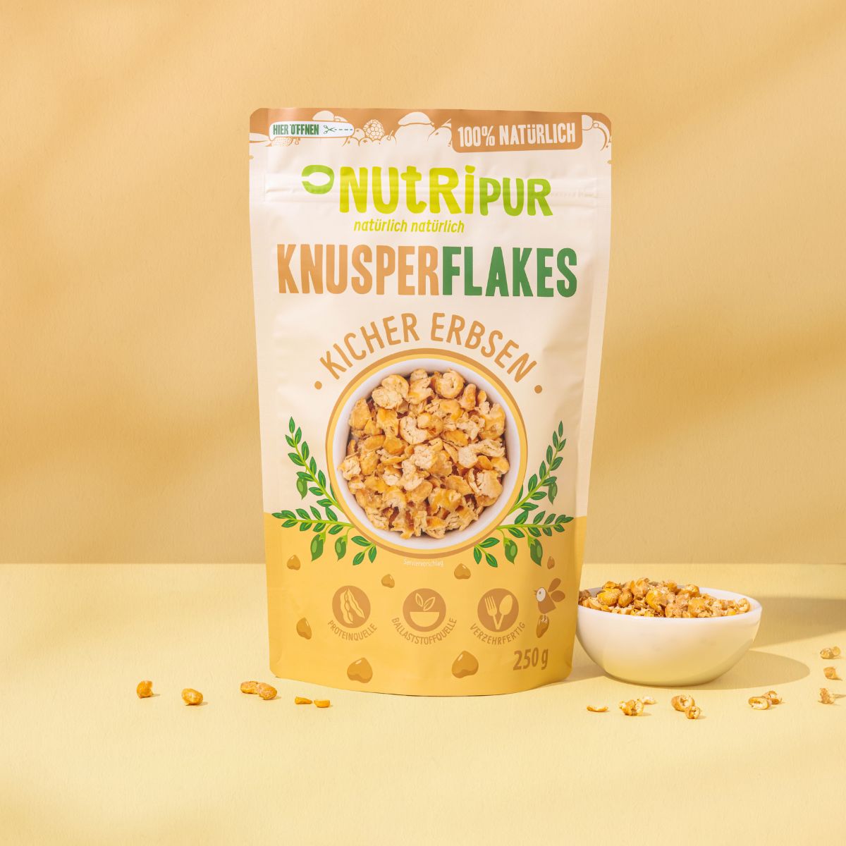 Beutel mit Knusperflakes Kichererbsen. Marke NutriPur. Aufschrift: 100% natürlich. Inhalt: 250g. Auf dem Beutel ist eine Schüssel mit Flakes abgebildet.