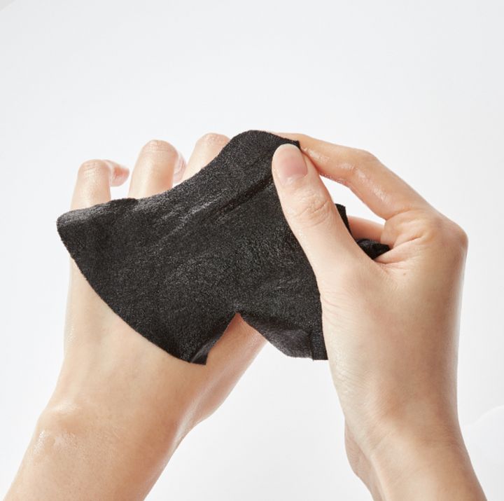 Hände halten eine schwarze Gesichtsmaske. Die Maske ist aus schwarzem Material gefertigt und leicht feucht.