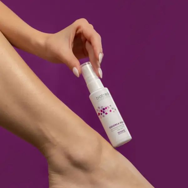 Weißes Spray wird von einer Hand über einem Bein gehalten. Beschriftung: Biotrade, Odorex Foot, Antitranspirant, 10 Tage Schutz.