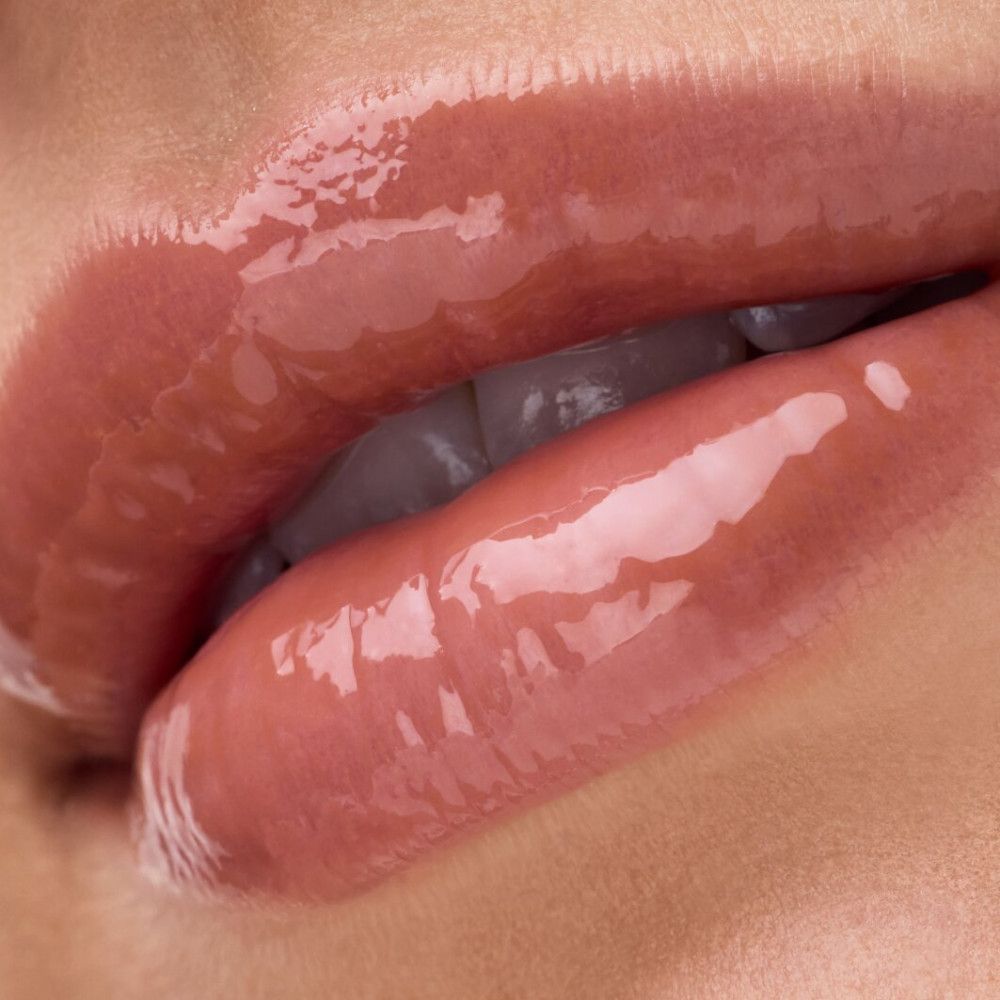 Nahaufnahme von Lippen mit glänzendem Lipgloss. Die Lippen sind leicht geöffnet, der Glanz ist deutlich sichtbar.