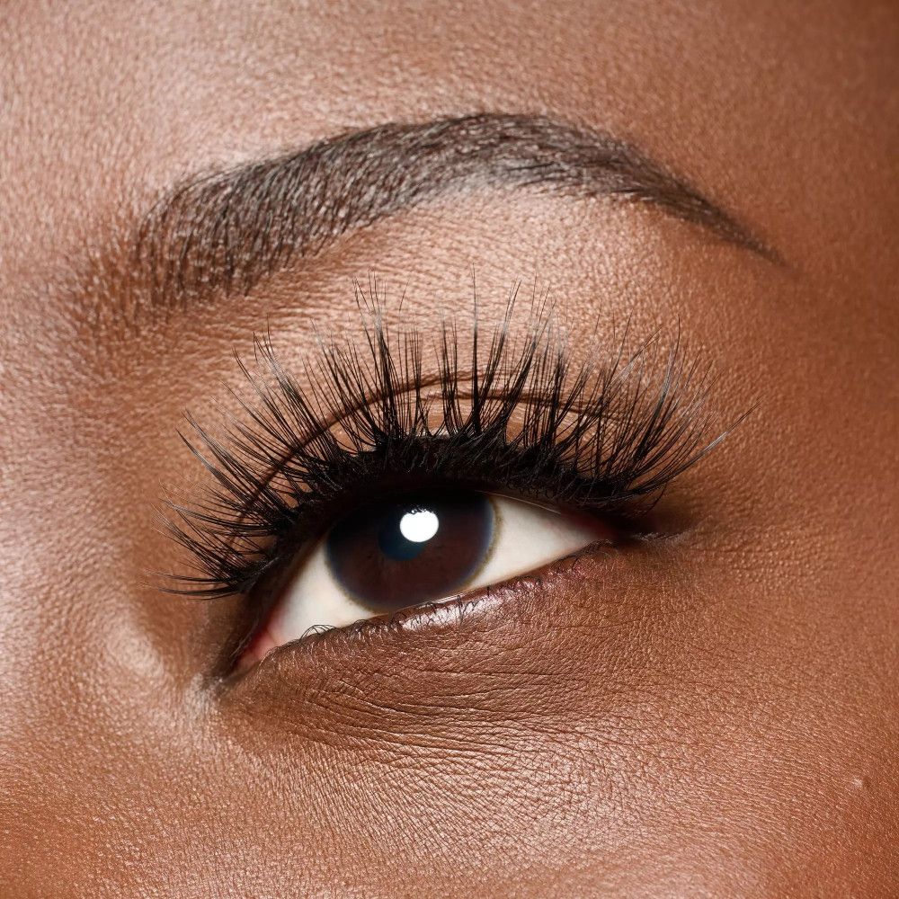 Auge mit angebrachten falschen Wimpern. Die Wimpern sind schwarz und verlängern die natürlichen Wimpern.