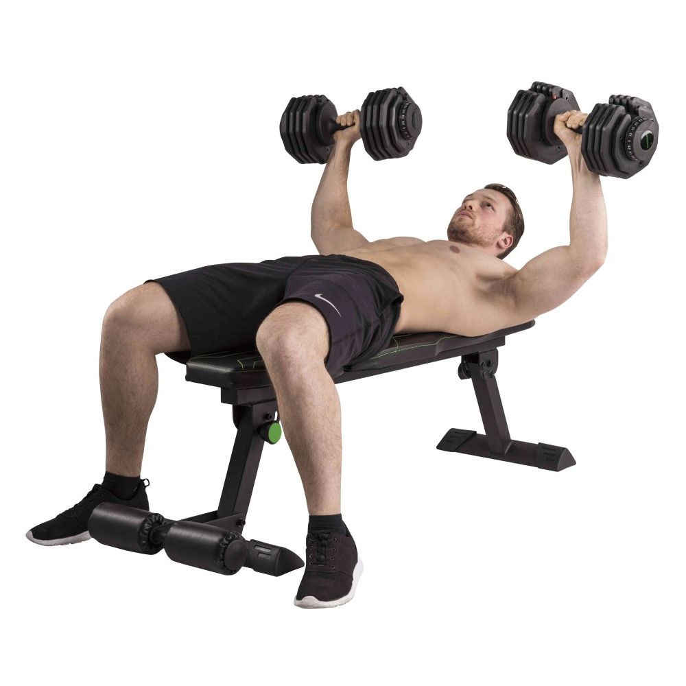 Flachbank mit Mann, der Bankdrücken macht. Schwarze Bank mit grünen Akzenten. Mann liegt auf der Bank.