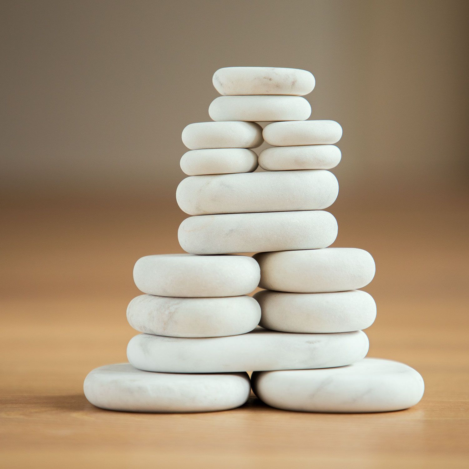 Turm aus weißen, ovalen Steinen, auf Holzuntergrund. Steine unterschiedlicher Größe gestapelt.