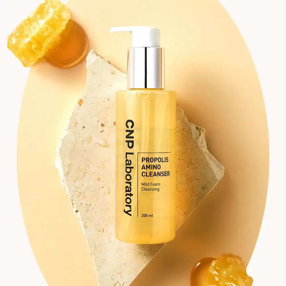 Gelbe Flasche mit Pumpe. Aufschrift: CNP Laboratory, Propolis Amino Cleanser, Mild Foam Cleansing. 200 ml. Auf Stein.