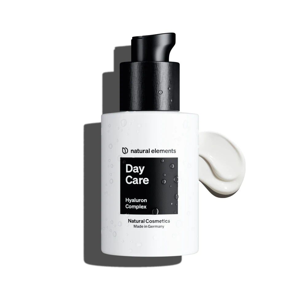 Weiße Flasche mit schwarzem Pumpkopf. Aufschrift: Day Care, Hyaluron Complex, Natural Cosmetics. Creme daneben.