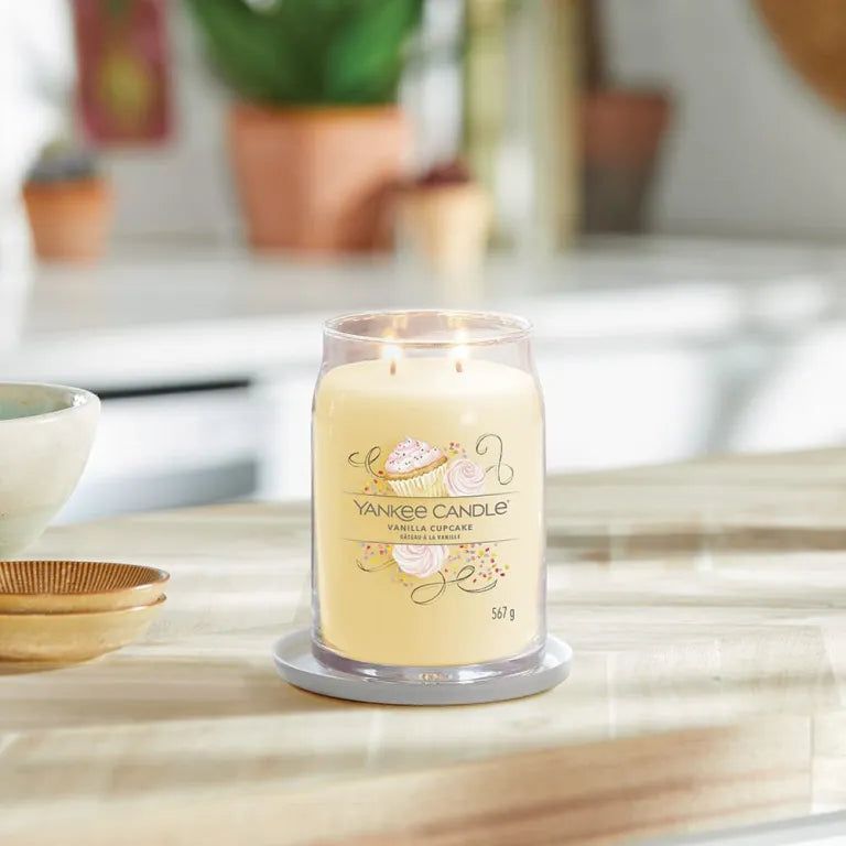 Yankee Candle Vanilla Cupcake Kerze in einem transparenten Behälter auf einem Tisch. Aufschrift: 567 g.