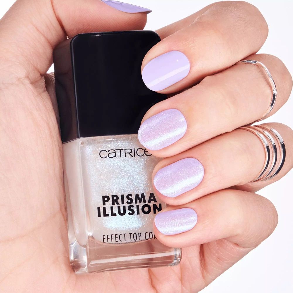 Catrice Prisma Illusion Effekt Top Coat. Flasche in Hand, lackierte Nägel. Lila Nagellack. Produktname deutlich sichtbar.