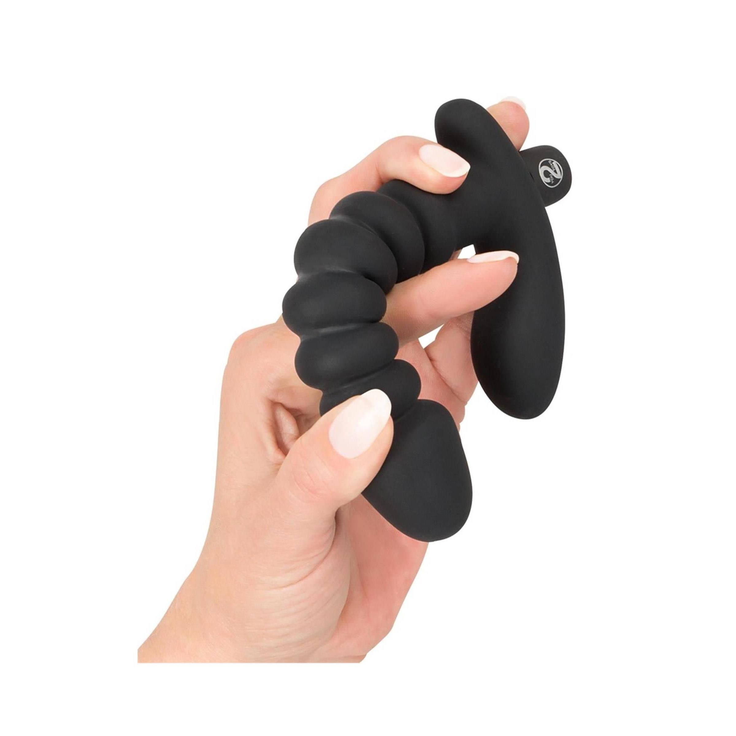 Hand hält schwarzen Vibrator mit Reizanker. Zylindrischer Schaft mit Rillen, gebogene Basis.
