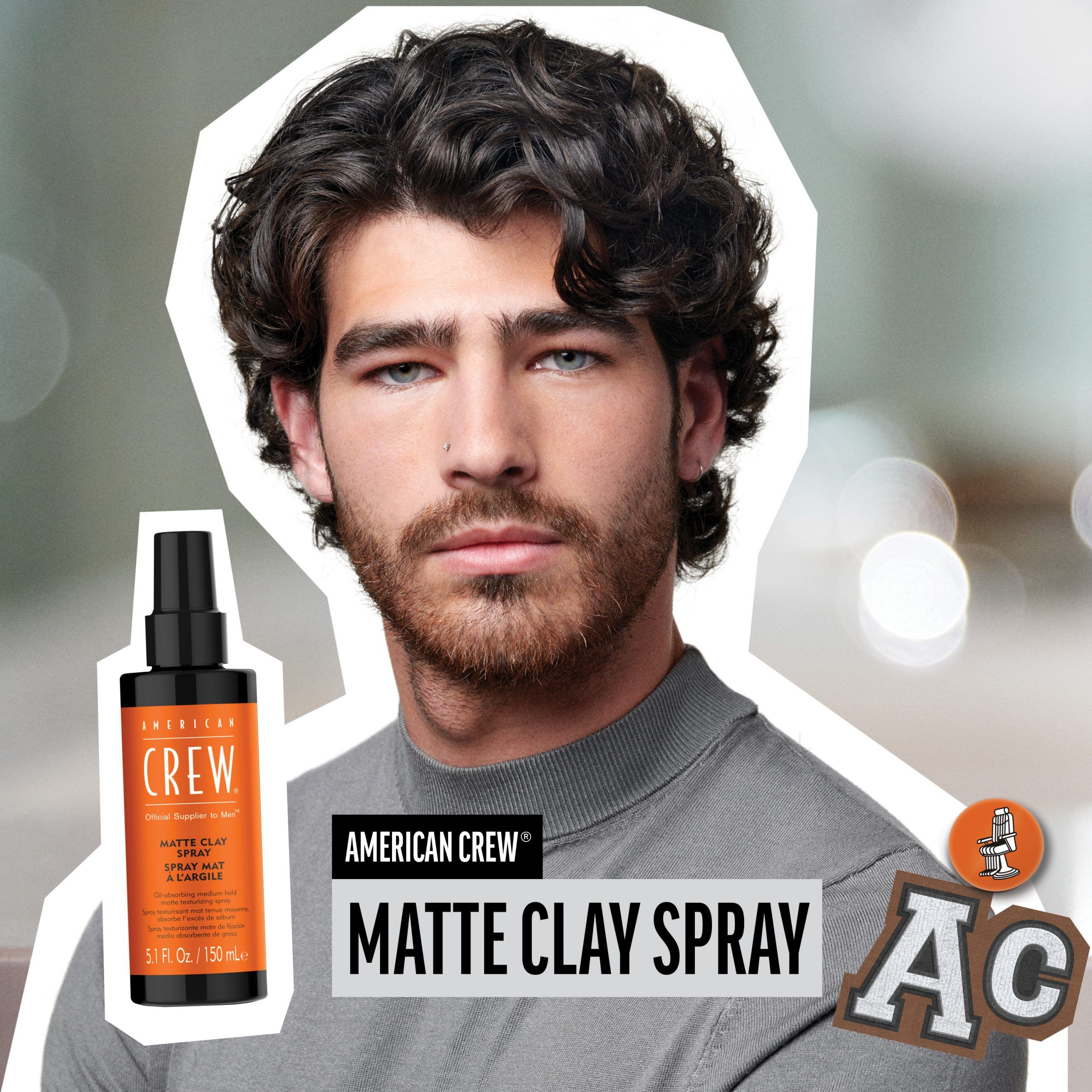 Mann mit lockigem Haar. AMERICAN CREW MATTE CLAY SPRAY. Schwarze Flasche, orangefarbenes Etikett. Text: MATTE CLAY SPRAY.
