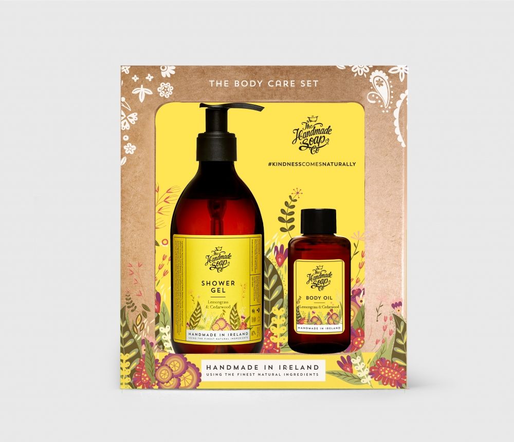 Geschenkset mit Duschgel und Körperöl in braunen Flaschen mit gelben Etiketten. Verpackt in einer Geschenkbox mit floralem Design.