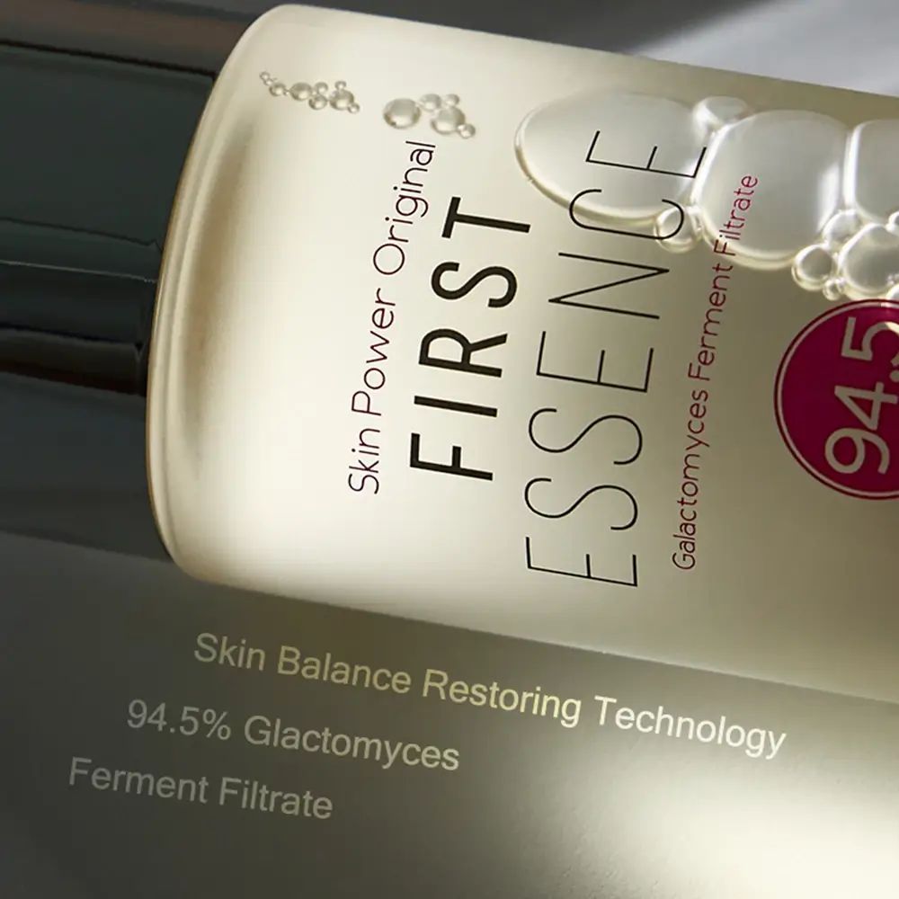 Nahaufnahme einer Hautpflege-Essenz-Flasche. Aufschrift: First Essence, 94,5% Galactomyces Ferment Filtrate.